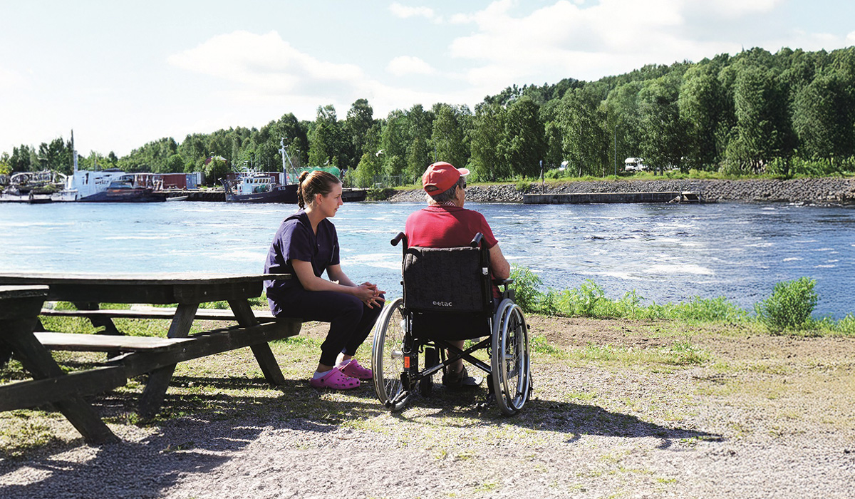 En tjej som tar med en äldre person på en dagstur vid älven.